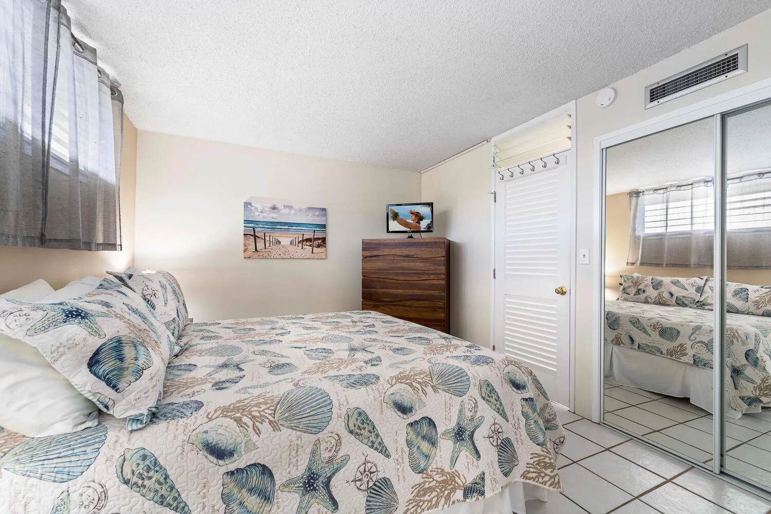 A bedroom with a bed covered in patterned bedding and a mirrored closet.