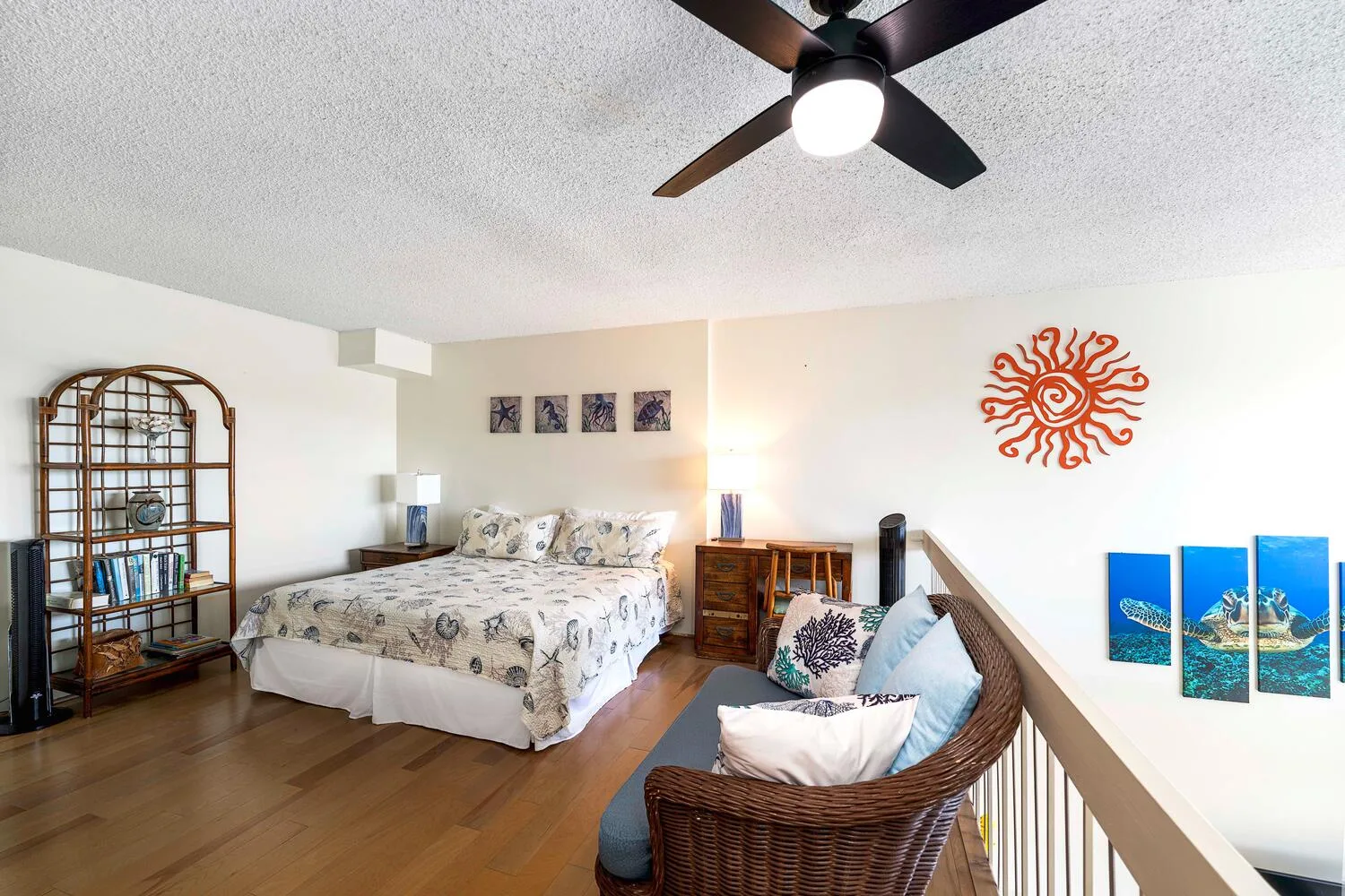A bright bedroom with a large bed and a wicker seating area.
