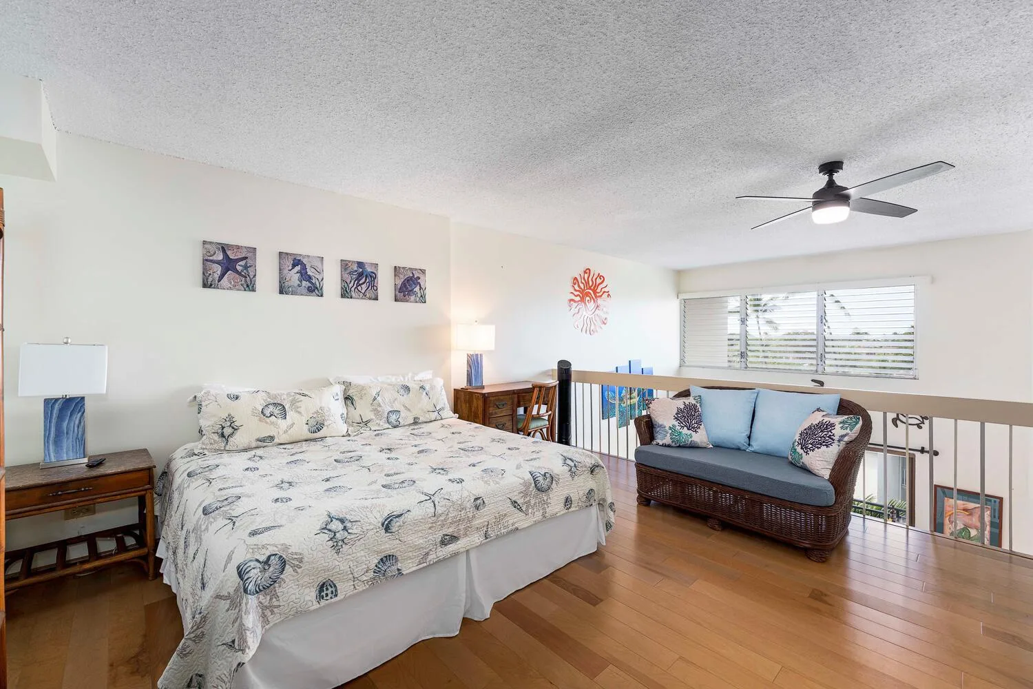A bedroom with a bed and a blue cushioned seating area by the window.
