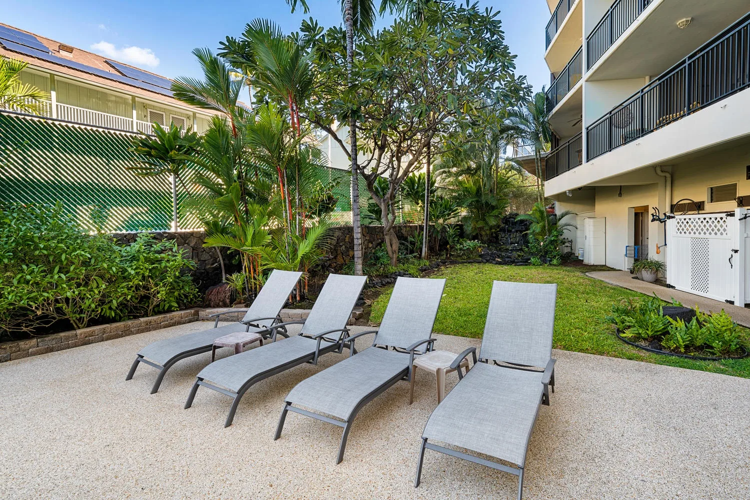 An outdoor lounge area with reclining seating beside a landscaped garden.