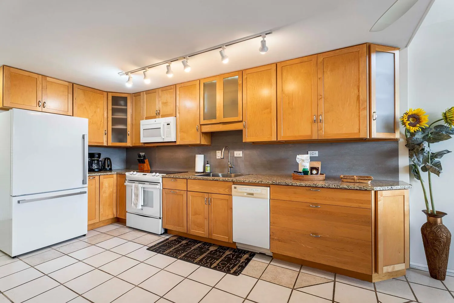 A kitchen with wooden cabinets, a refrigerator, and a long countertop.