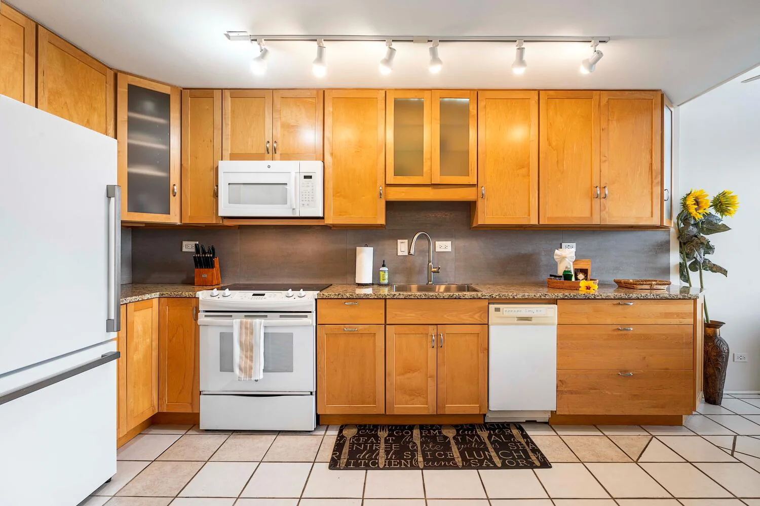 A kitchen with wooden cabinets, light countertops, and stainless-steel appliances.