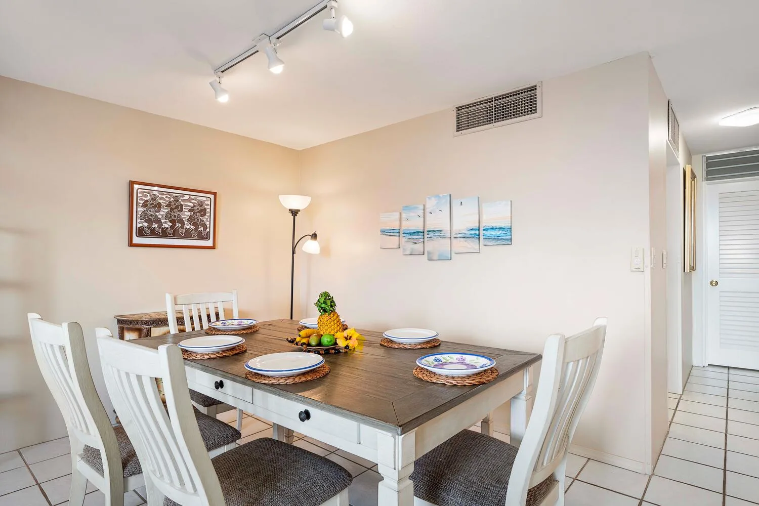 A dining area with a set table and framed artwork on the walls.