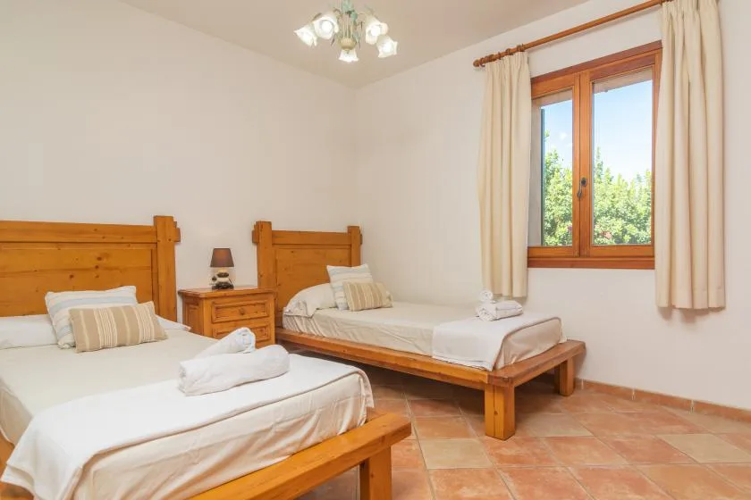 Un dormitorio con dos camas de madera, ropa de cama blanca y una ventana con cortinas.