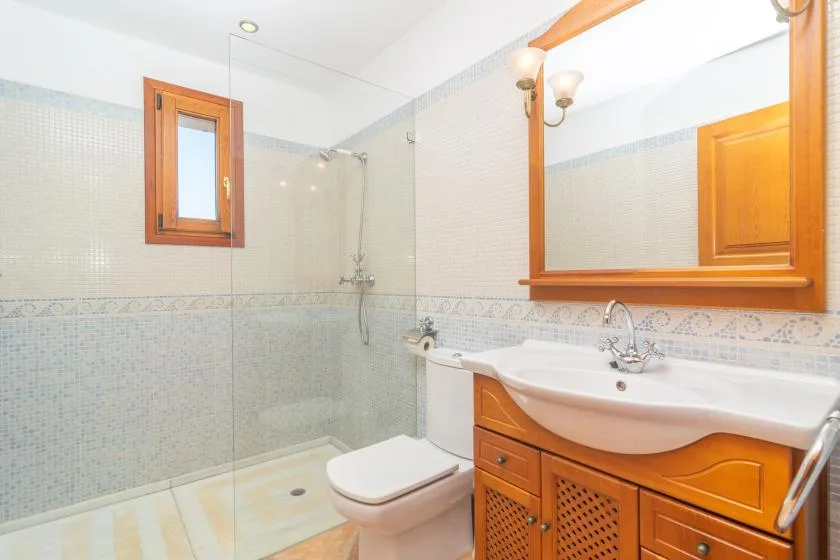 Un baño con azulejos, ducha de vidrio, inodoro y lavabo.