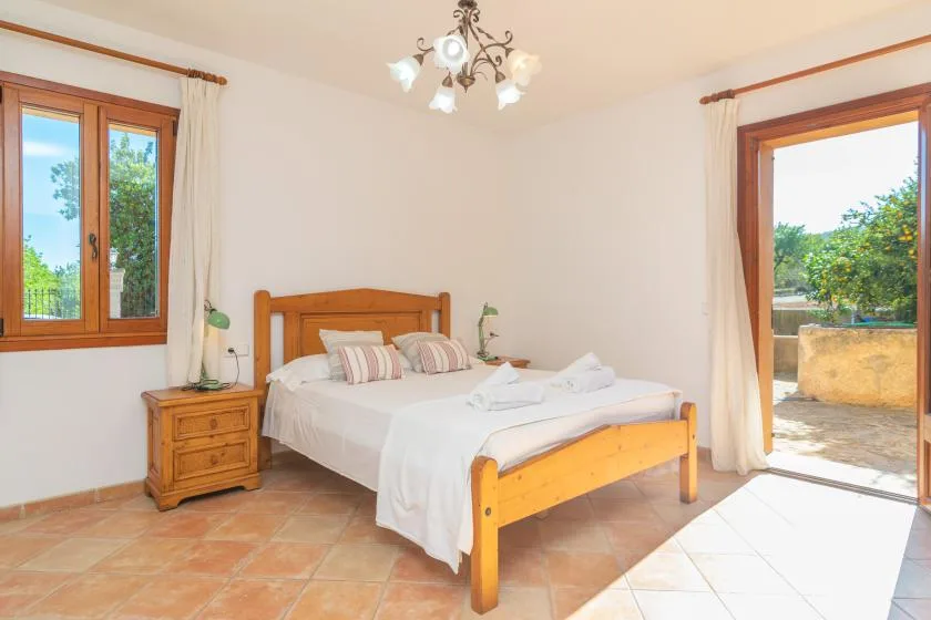 Un dormitorio luminoso con una cama de madera y ventanas con vistas a la vegetación.