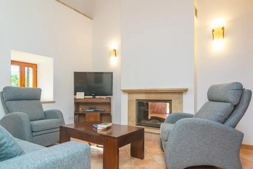Una sala de estar con asientos grises, una mesa de centro y una chimenea.