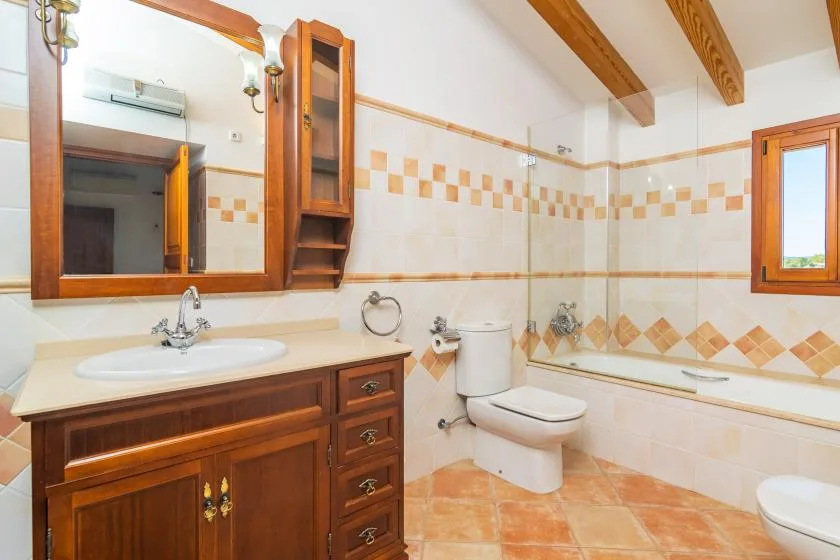 Un baño de azulejos con mueble de madera, inodoro y bañera.