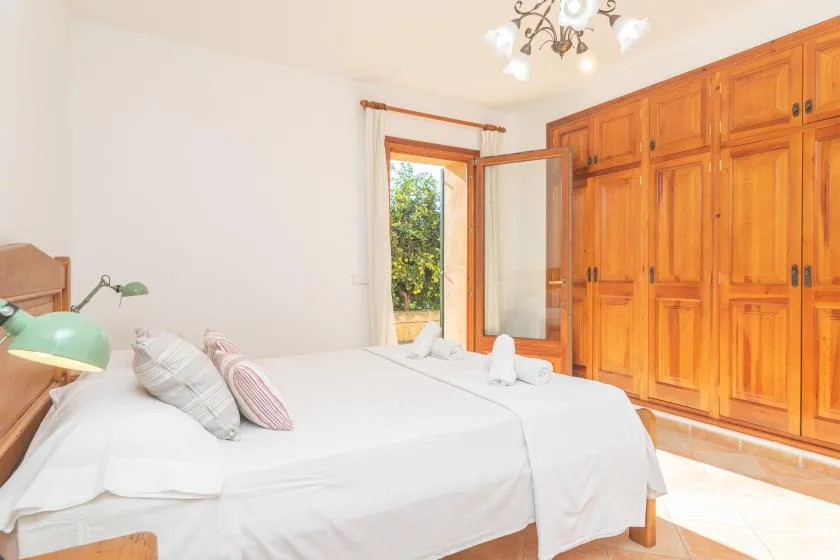 Un dormitorio con camas junto a armarios de madera y una ventana abierta.