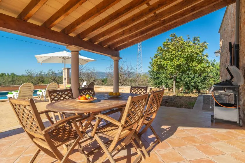 Una zona de comedor exterior cubierta con una mesa y sillas de madera.
