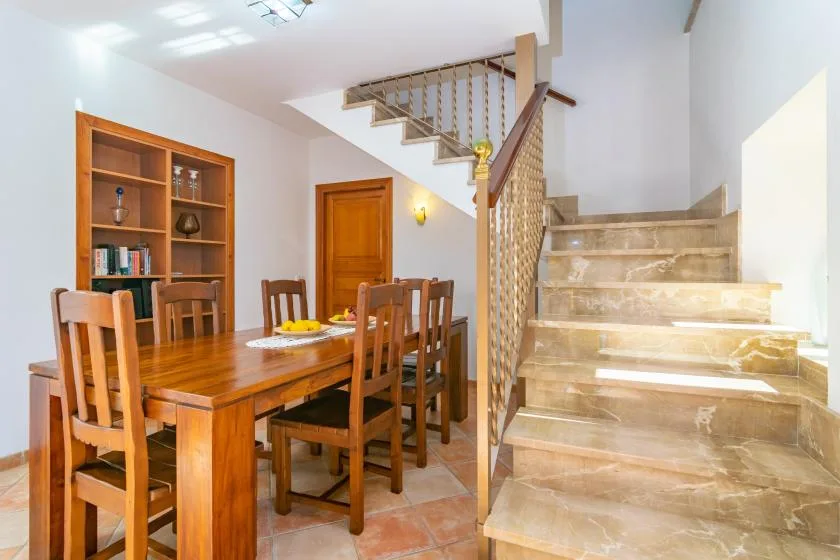 Un comedor con una mesa de madera y sillas junto a una escalera.