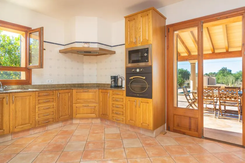 Una cocina con gabinetes de madera y horno empotrado da a un patio.