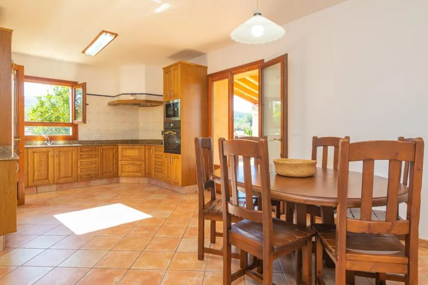 Una cocina y comedor luminosos con armarios de madera y una mesa de comedor.