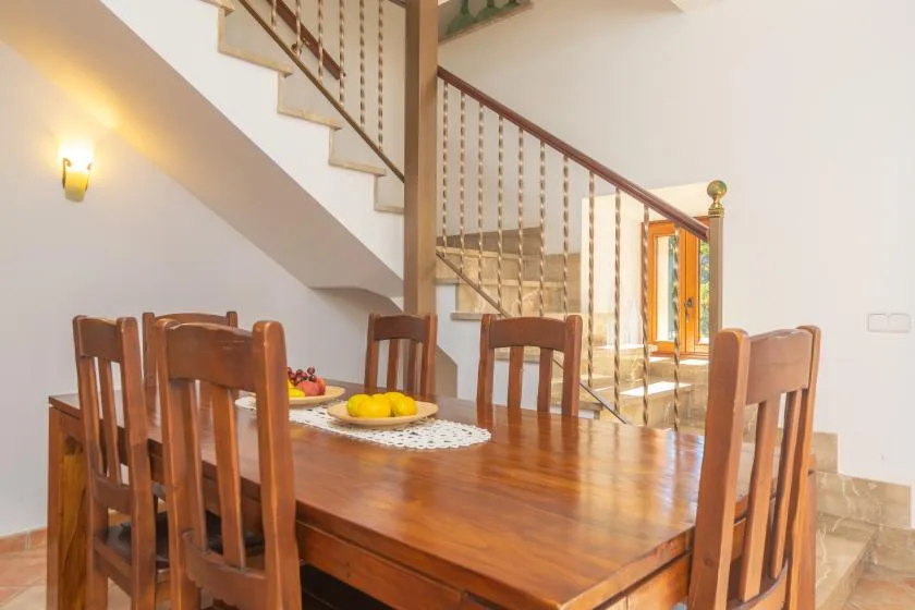 Una mesa de comedor de madera y sillas están bajo una escalera.