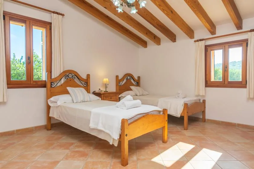 Un dormitorio con dos camas individuales bajo vigas de madera vistas.