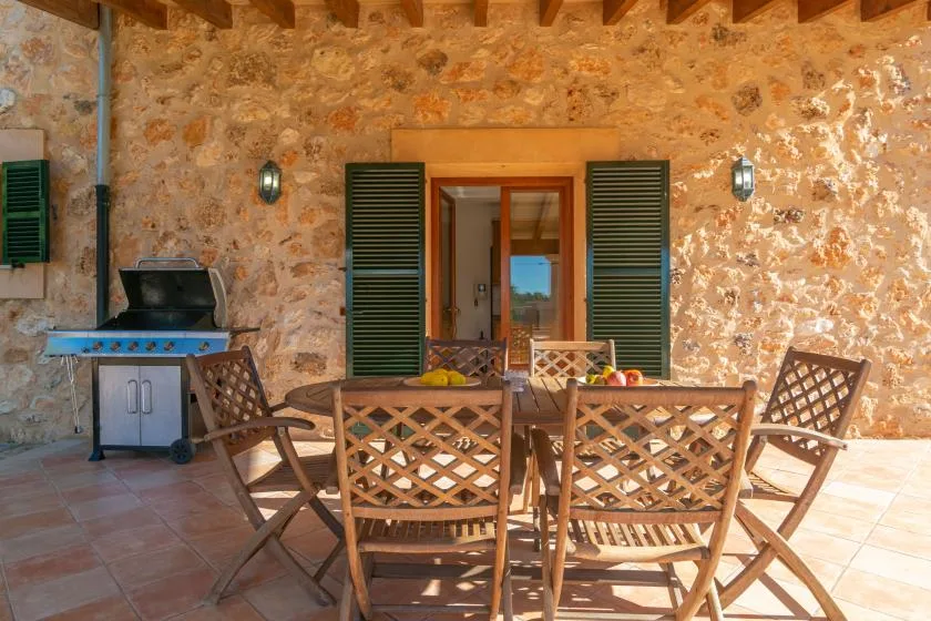 Un patio cubierto de piedra con asientos al aire libre, una mesa y una parrilla.