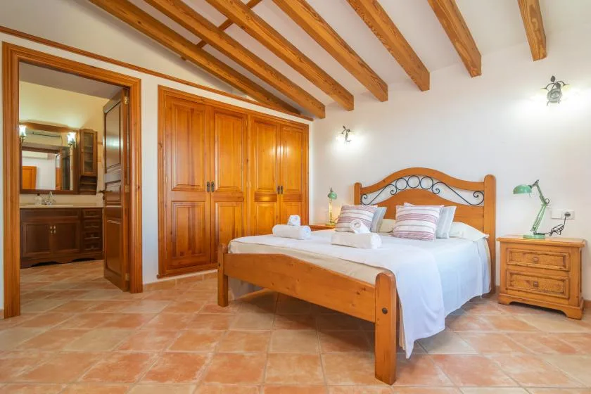 Un dormitorio con una cama de madera bajo vigas vistas en el techo.