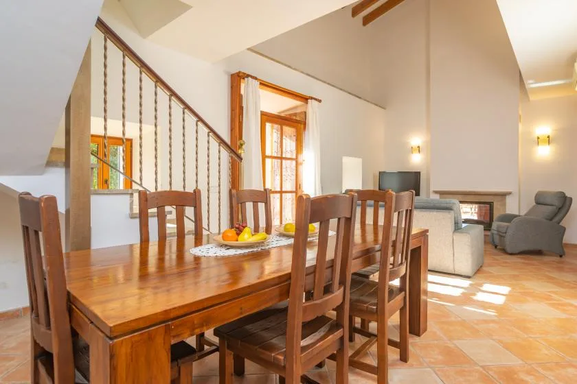 Un comedor con una mesa y sillas de madera junto a una escalera.