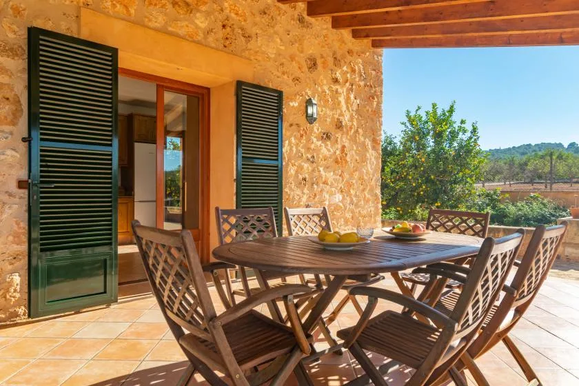 Un comedor al aire libre con una mesa de madera y asientos junto a un muro de piedra.