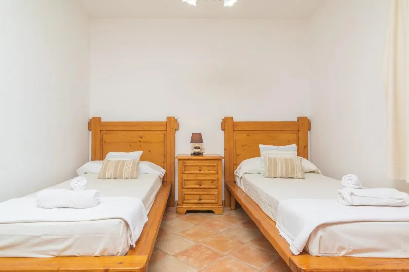 Un dormitorio con dos camas individuales y una mesita de noche de madera.