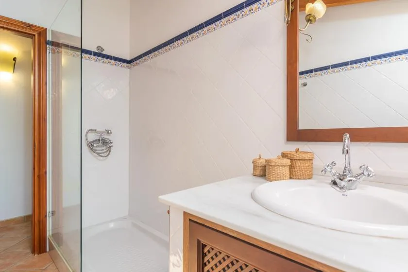 Un baño con ducha, lavabo y un gran espejo de pared.