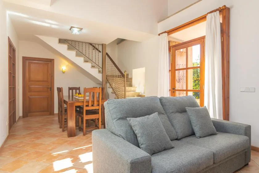 Una sala de estar y comedor con asientos grises junto a una mesa de comedor de madera.