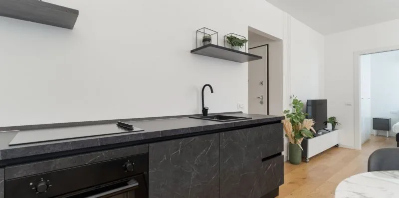 Una cocina moderna con gabinetes oscuros, una placa de cocina y un fregadero.