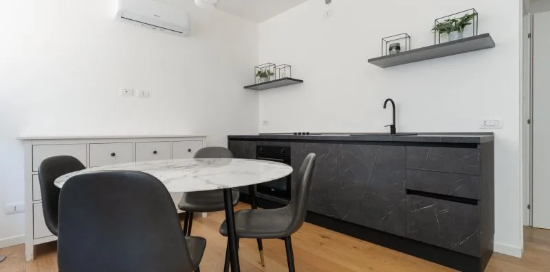Una mesa de comedor y asientos están junto a una encimera oscura.
