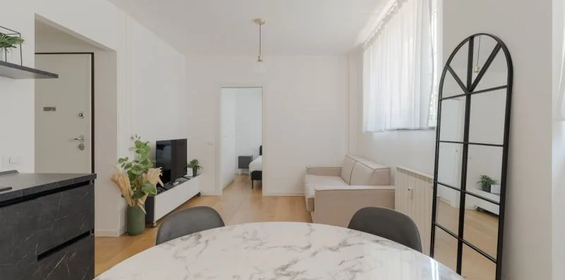 Una luminosa sala de estar y comedor con una mesa redonda y asientos claros.