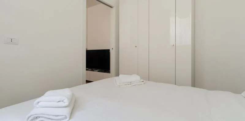 Un dormitorio con una cama bien hecha y toallas dobladas.