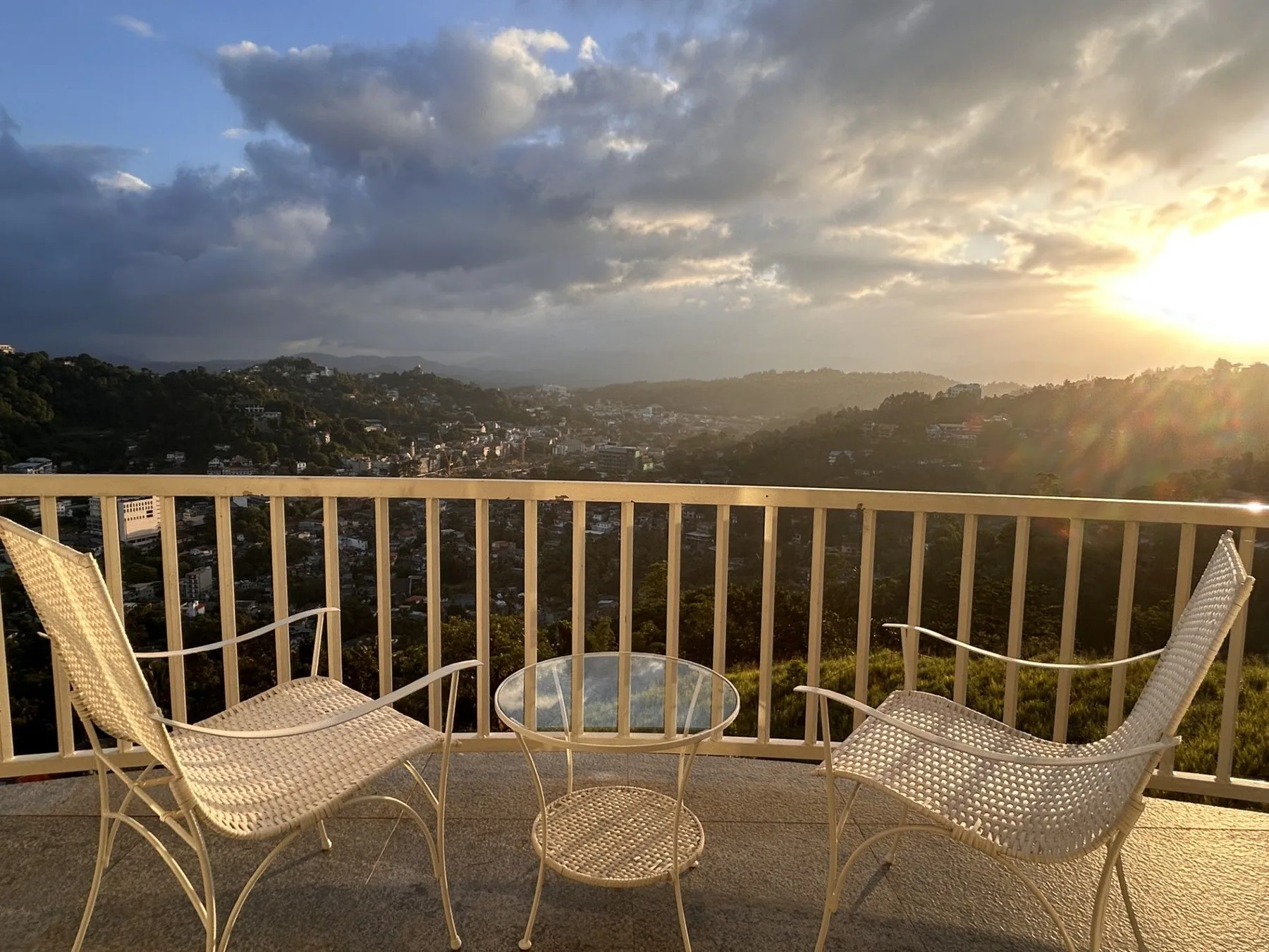 Balcón privado con sillas y vistas a las colinas de Kandy al atardecer