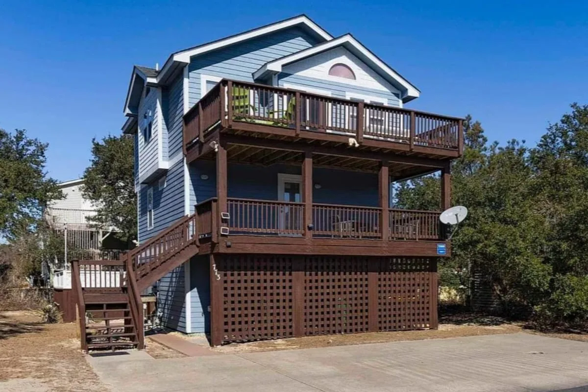 Una casa azul con dos porches de madera y una escalera exterior.