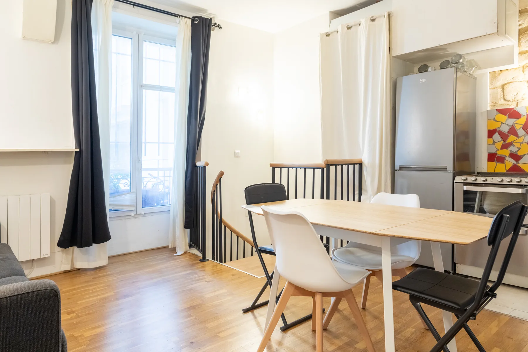 A bright dining area with a wooden table beside a large window.