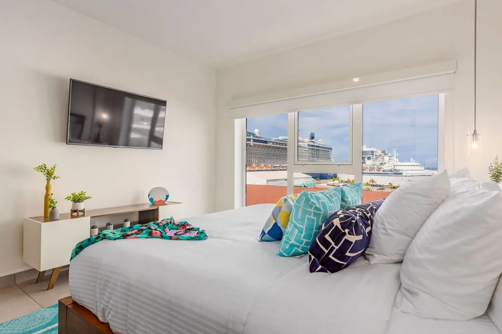 Wake up to crisp white linens, bright natural light, and stunning views of cruise ships gliding by from your coastal bedroom retreat.
