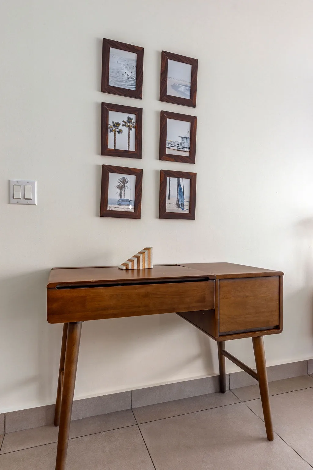 Stylish coastal retreat vibe in this entryway. The beach-themed gallery wall and sleek mid-century desk set the tone for relaxation ahead.