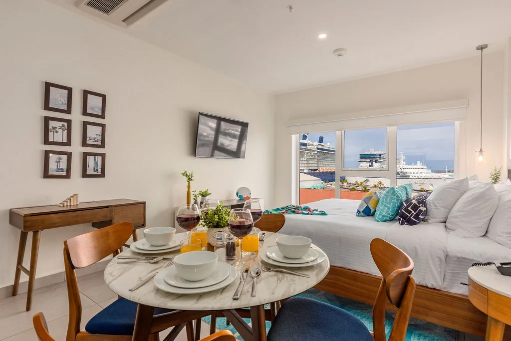Settle into your bright, modern living space where harbor views and cheerful pops of color create the perfect backdrop for morning coffee or evening wine as cruise ships glide by.