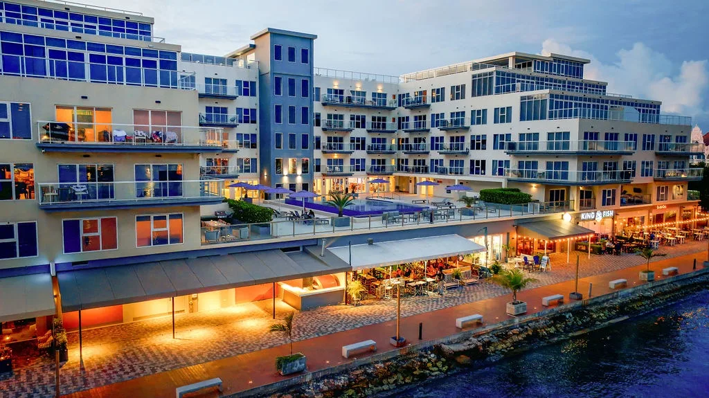 Modern waterfront property with vibrant dining spaces and contemporary architecture, located in a lively marina setting.