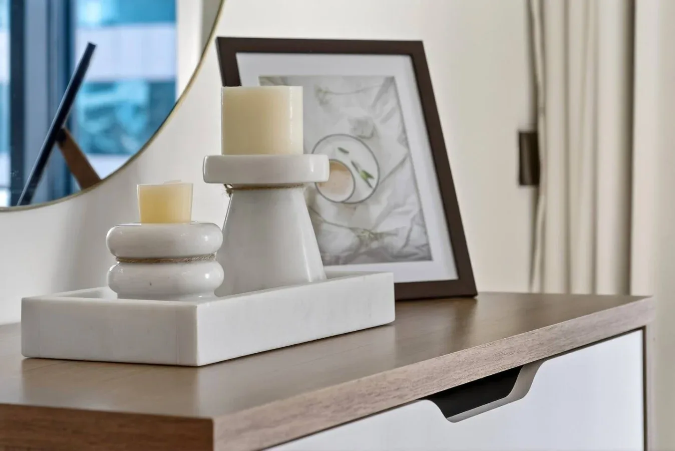 Decorative candles and a framed print sit on a console table.