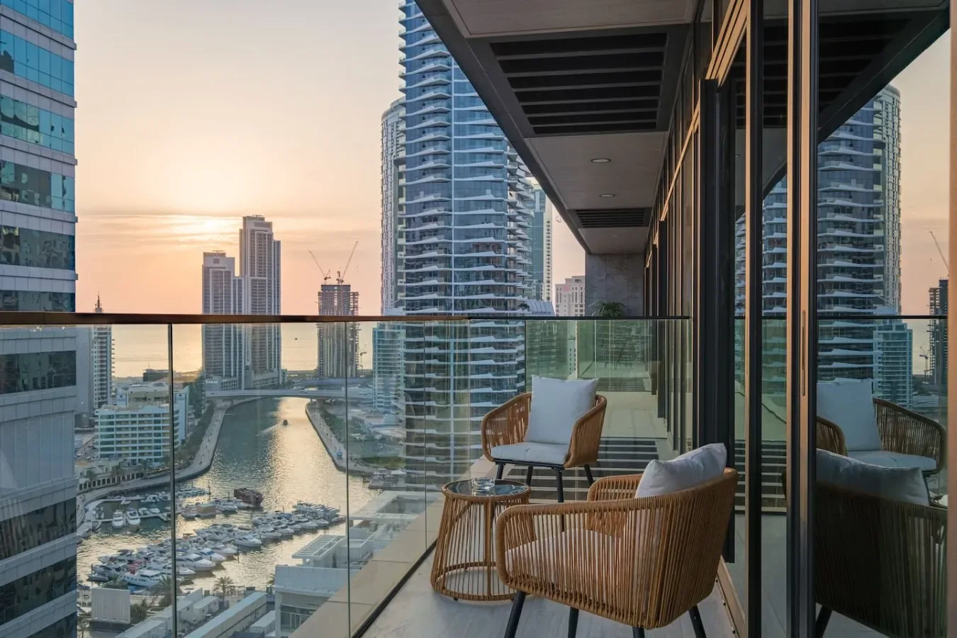 A balcony seating area overlooks the waterfront skyline at sunset.