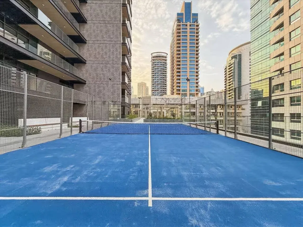 A blue outdoor court sits between tall buildings.