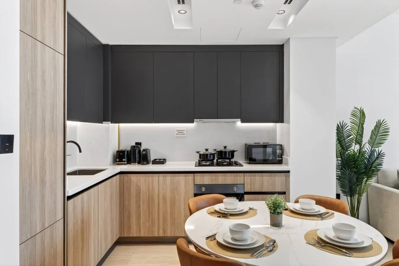 A modern kitchen with dark cabinets and a round dining table set for a meal.