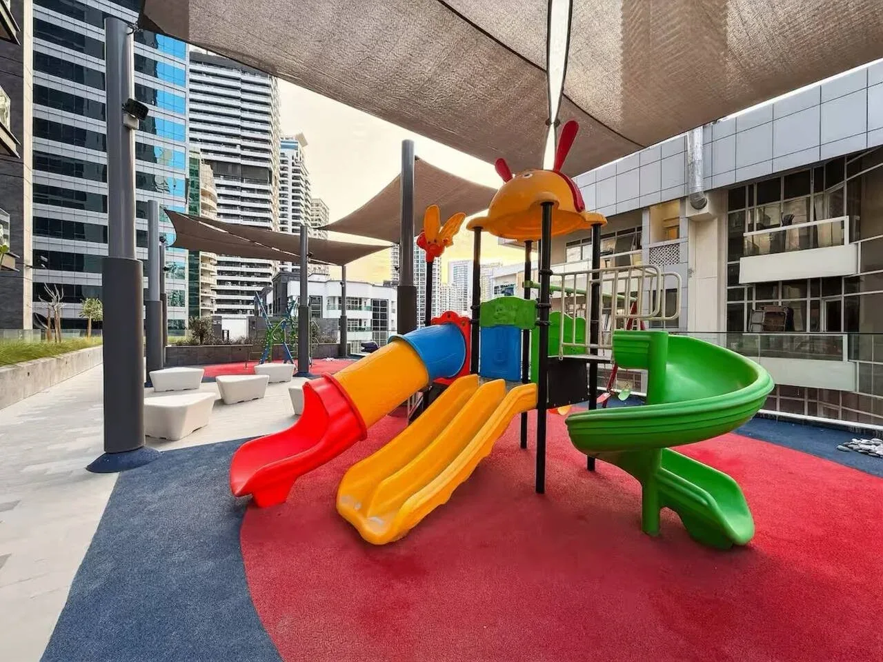 A colorful playground with slides and climbing equipment beneath shade canopies.