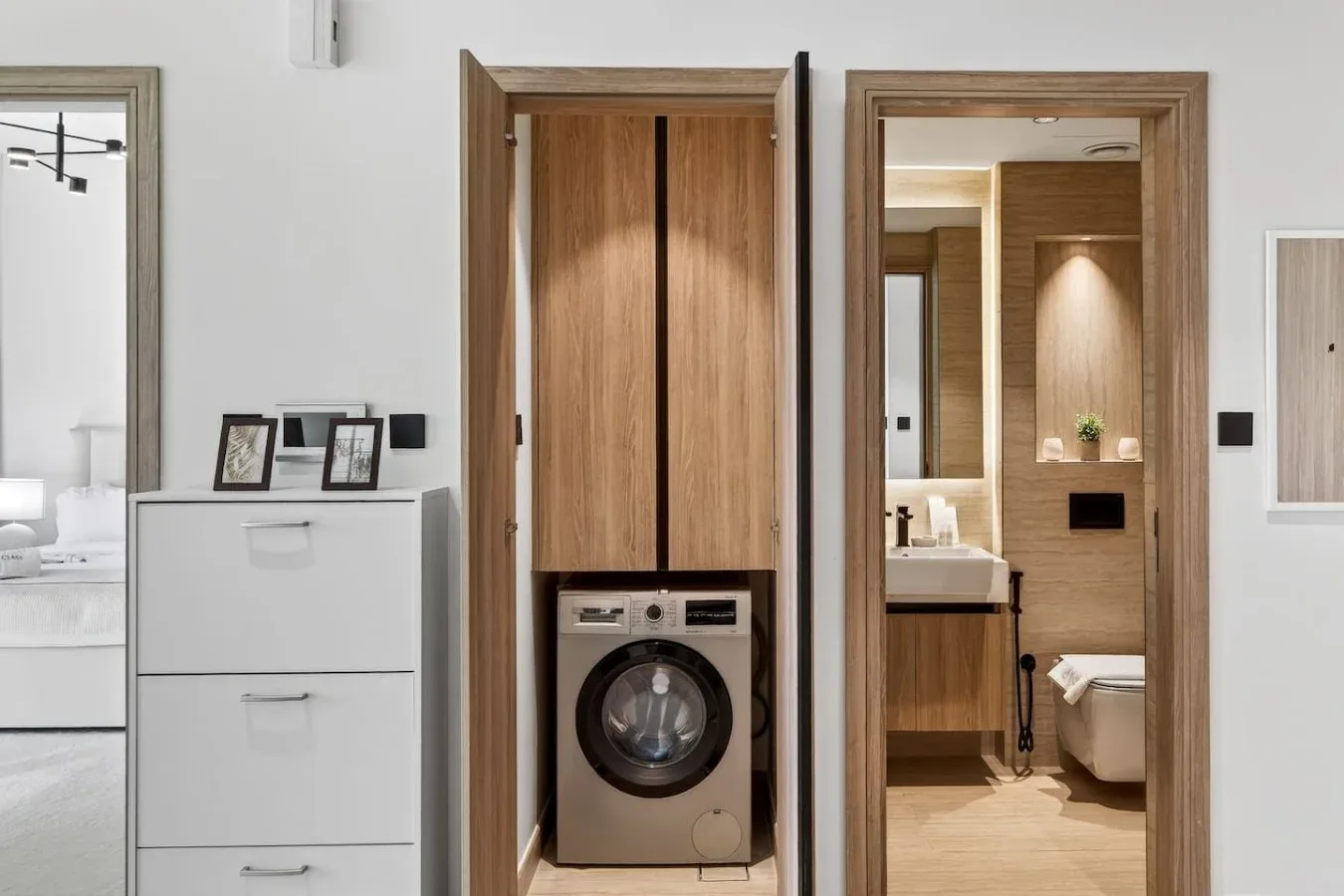 A laundry area with a front-loading washing machine beside a bathroom.