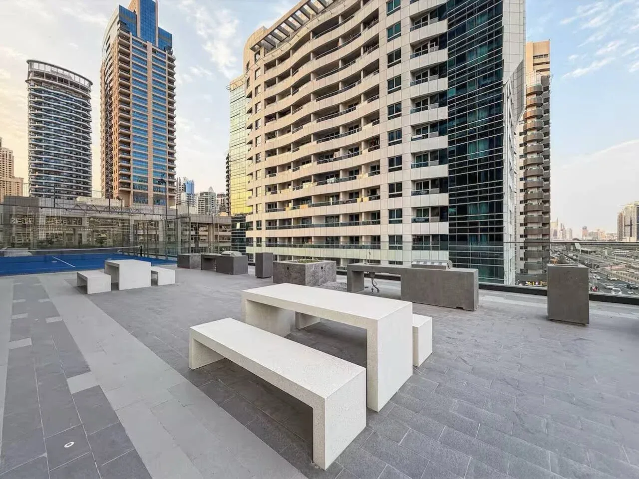 A rooftop terrace with pale seating and tall city buildings in the background.