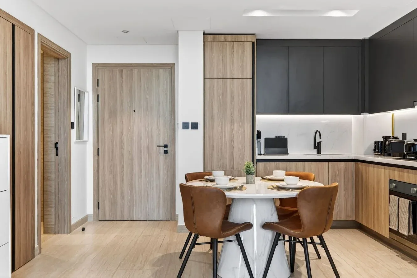 A modern kitchen and dining area with a round table and wood cabinetry.