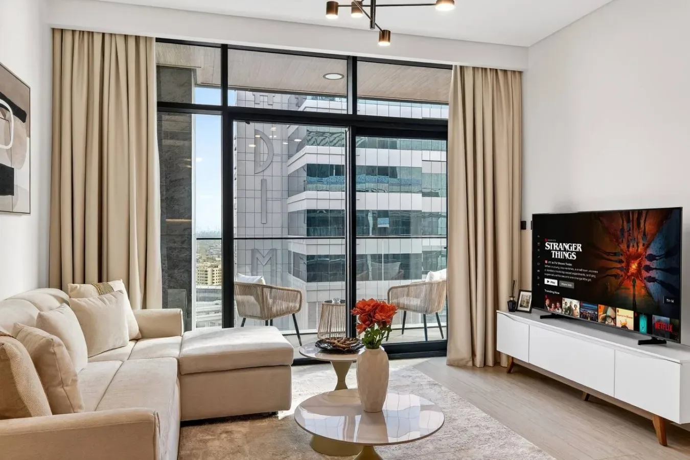 A bright living room with seating, a coffee table, and large windows.