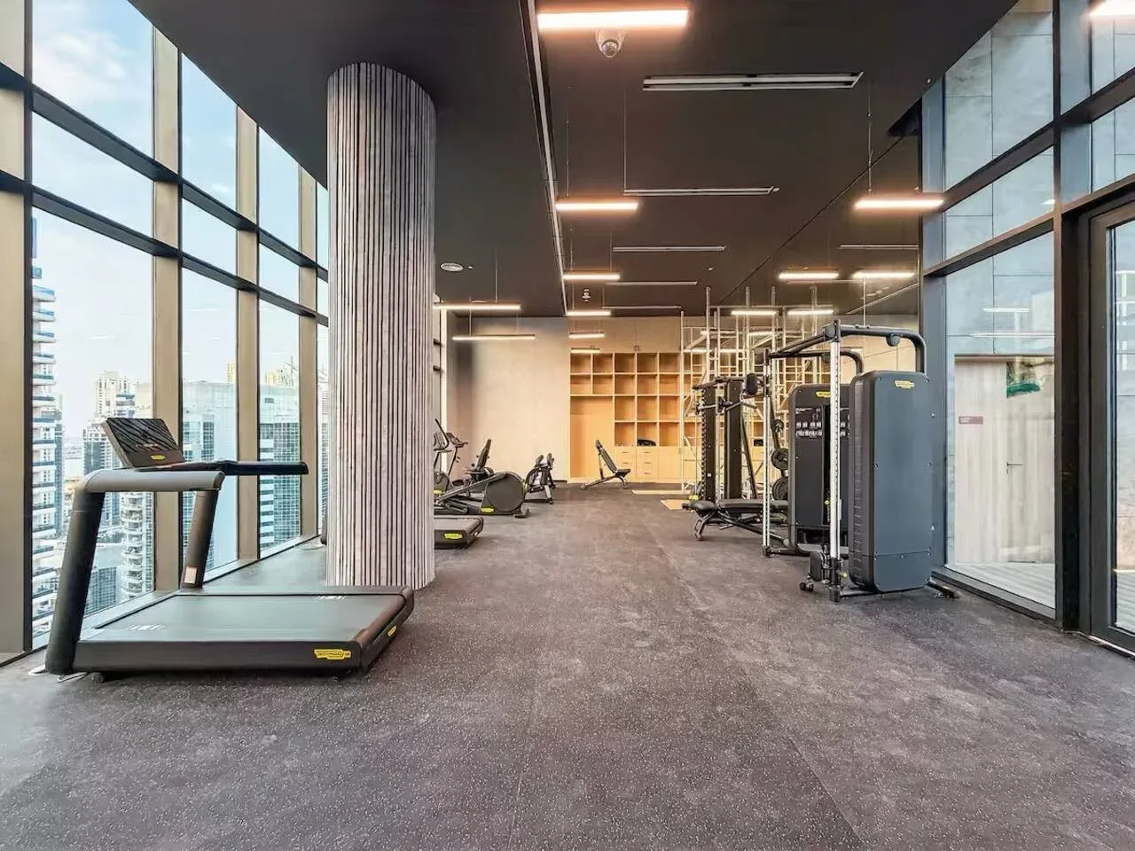 A gym with exercise equipment and floor-to-ceiling windows.