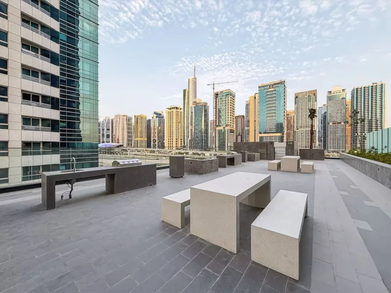A rooftop terrace with built-in seating overlooks a cluster of high-rise buildings.