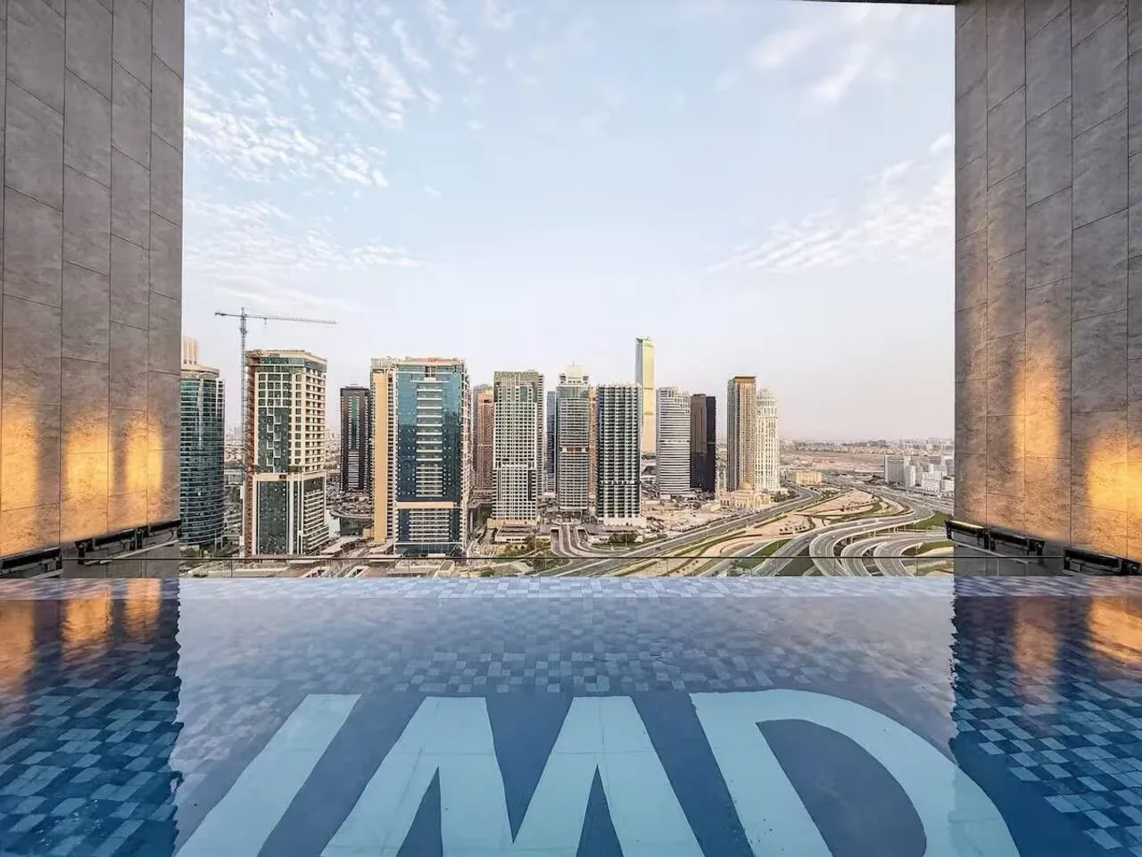 An infinity pool overlooks a city skyline and curving roads.