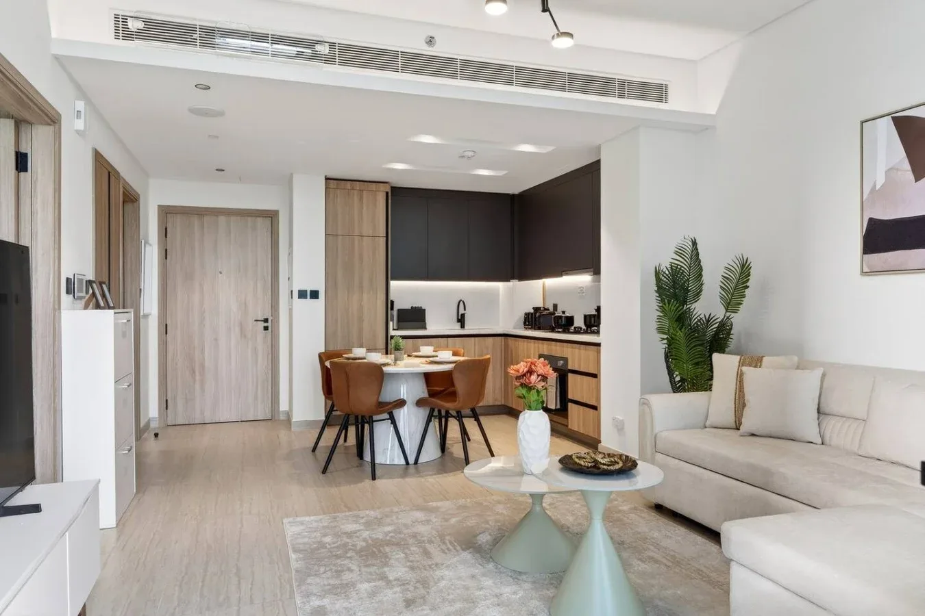 A bright open-plan living room and kitchen with a dining table and seating.